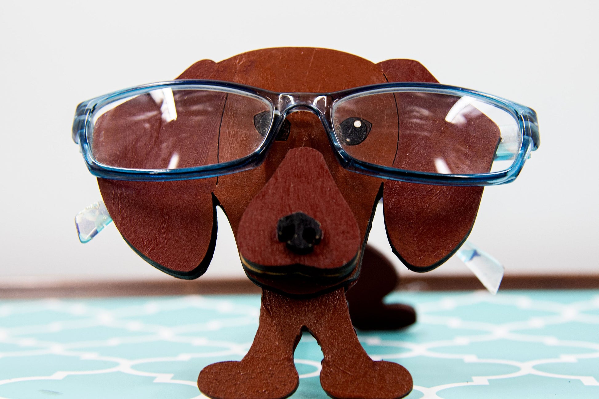 Cute wooden weiner dog eyeglass stand used as a quirky desk accessory for organizing glasses 