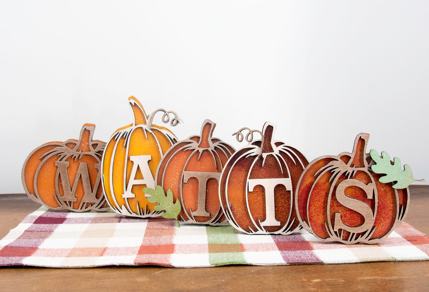 Custom standing wood pumpkins designed as individual letters to spell out names, fall words, or seasonal phrases. Each letter is crafted into a 3D pumpkin shape with intricate etched details, layered for dimension, and hand-painted in your choice of autumn colors. These personalized shelf sitters range in size from 3 to 6.5 inches and are perfect for mantels, entry tables, tiered trays, classrooms, or Thanksgiving displays. Ideal for gifting or adding a festive touch to your home.
