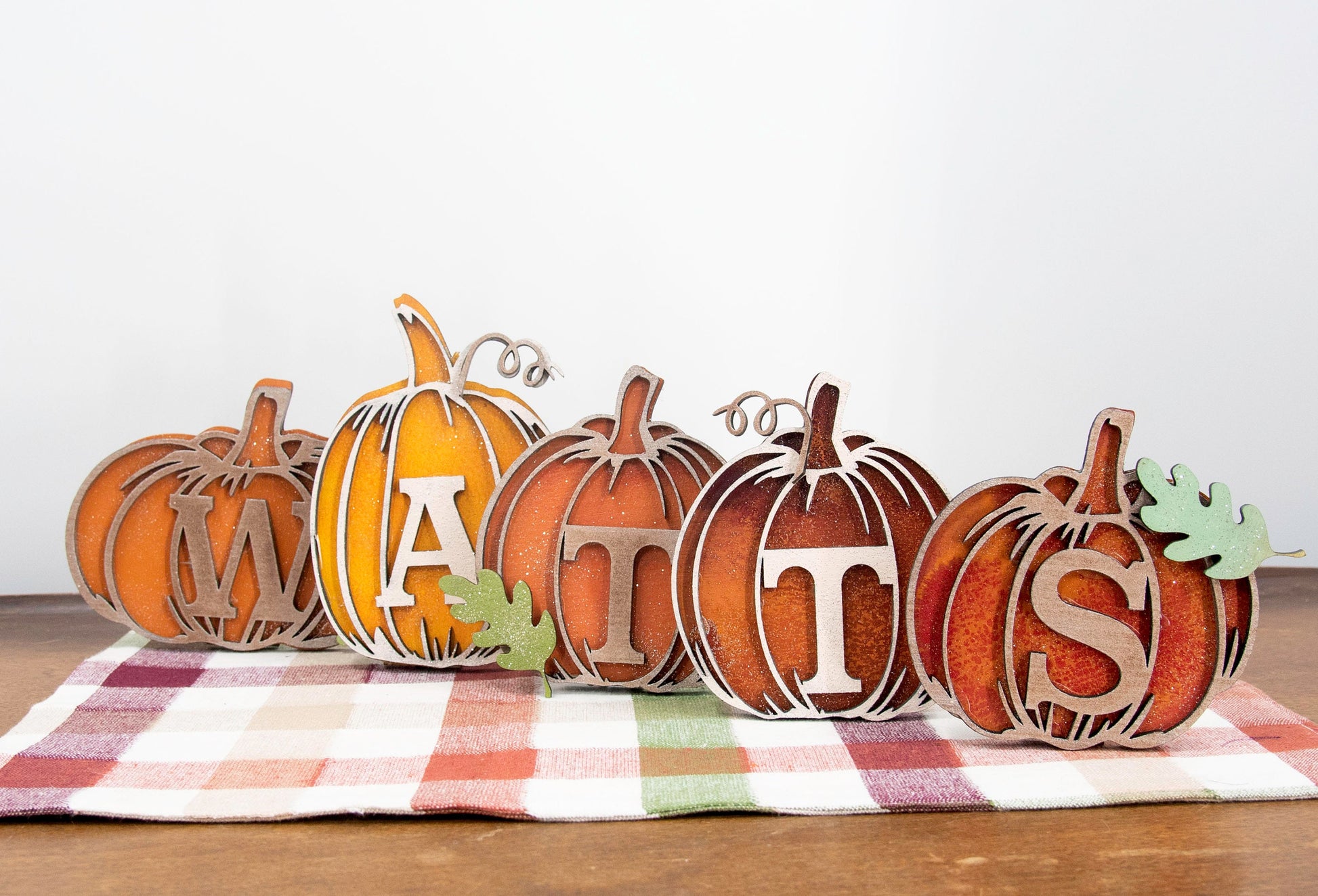 Custom standing wood pumpkins designed as individual letters to spell out names, fall words, or seasonal phrases. Each letter is crafted into a 3D pumpkin shape with intricate etched details, layered for dimension, and hand-painted in your choice of autumn colors. These personalized shelf sitters range in size from 3 to 6.5 inches and are perfect for mantels, entry tables, tiered trays, classrooms, or Thanksgiving displays. Ideal for gifting or adding a festive touch to your home.
